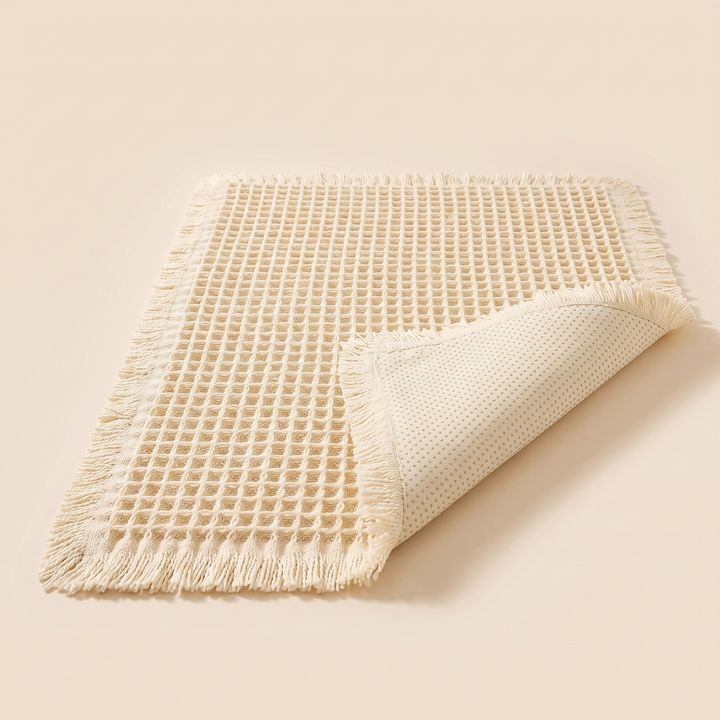 Waffle Bath Mat with Tassels in Cream – corner flipped up to show the dotted non-slip backing
