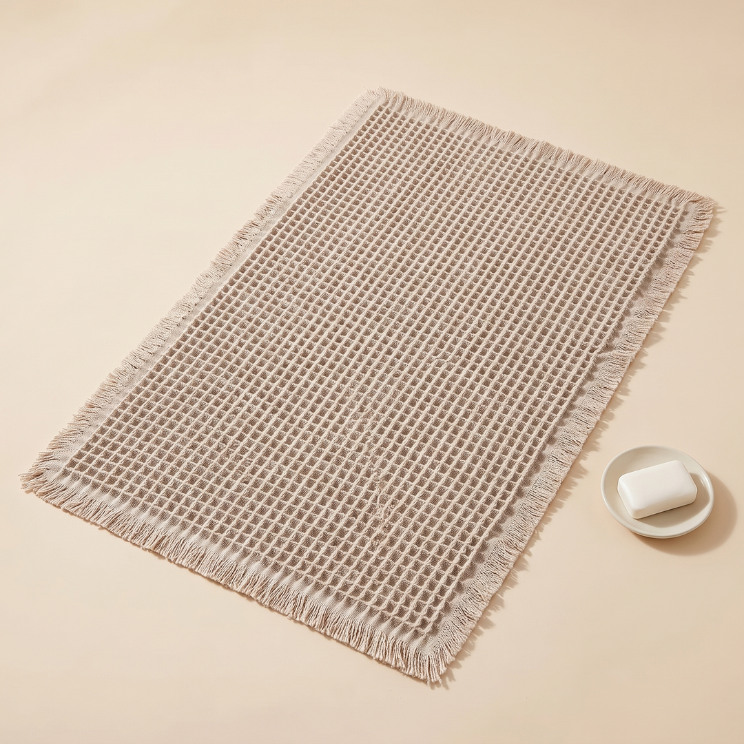 Waffle Bath Mat with Tassels in Oatmeal – beside a small dish holding a bar of soap