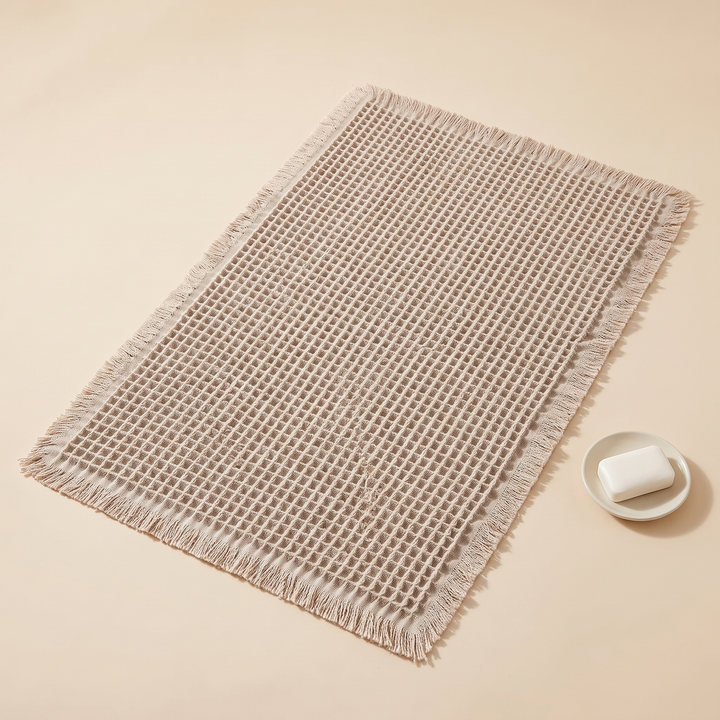 Waffle Bath Mat with Tassels in Oatmeal – beside a small dish holding a bar of soap
