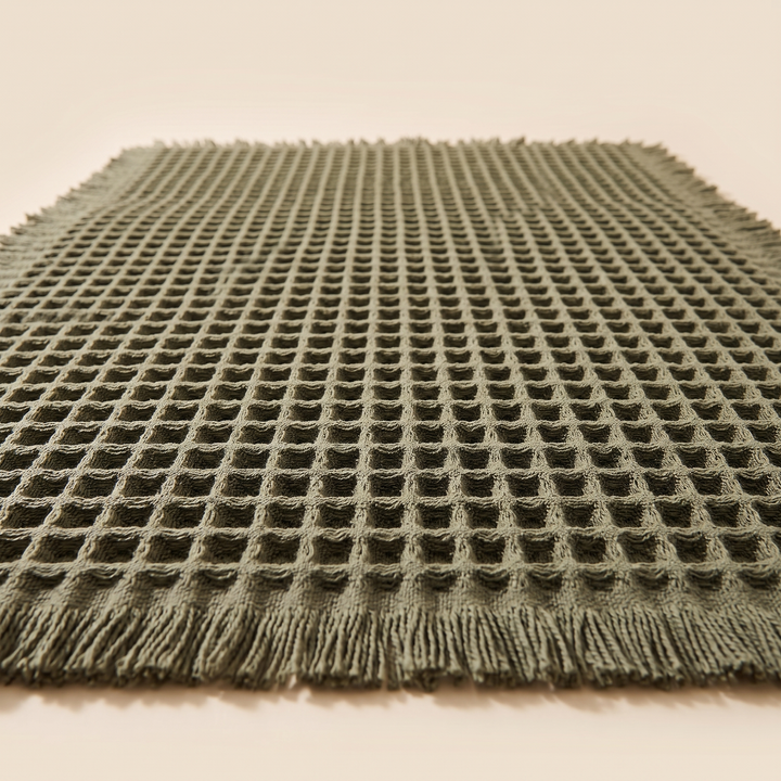 Waffle Bath Mat with Tassels in Olive Green – ground-level view of the waffle grid fading into soft focus