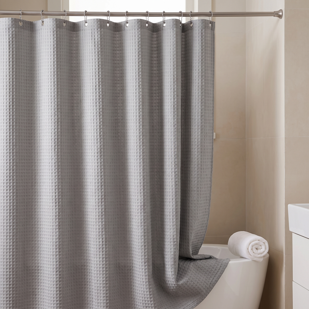 Fabric Shower Curtain – Waffle Weave in Gray – hem draping into tub beside rolled towel and vanity