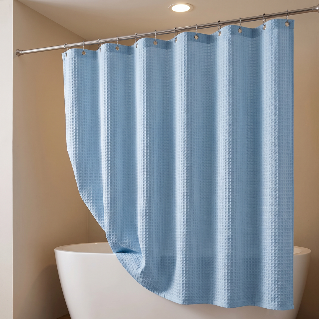Fabric Shower Curtain – Waffle Weave in Light Blue – diagonal drape with lifted corner above a freestanding tub