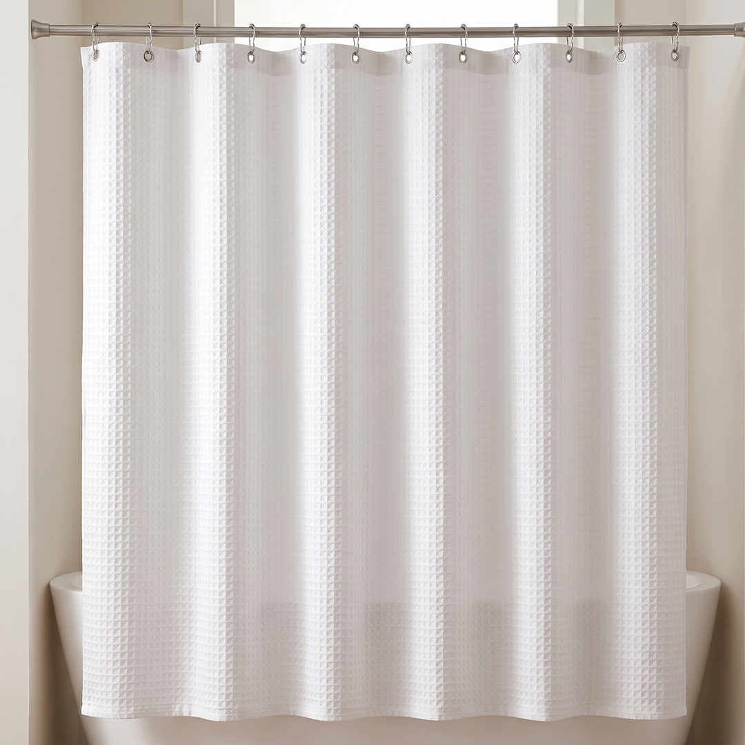 Fabric Shower Curtain – Waffle Weave in White – hanging from a rod over a bathtub, front view