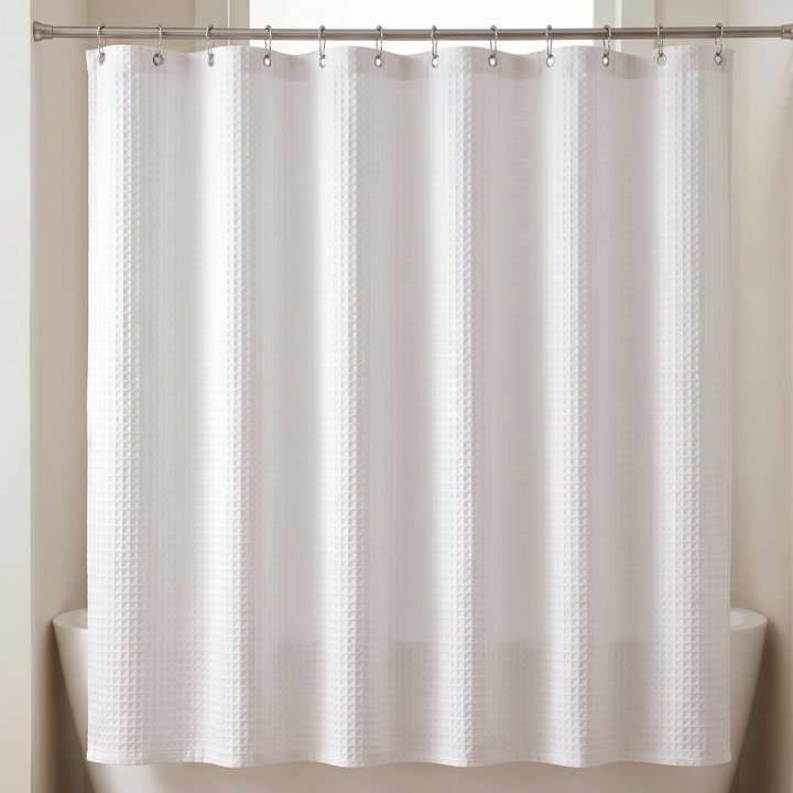 Fabric Shower Curtain – Waffle Weave in White – hanging from a rod over a bathtub, front view