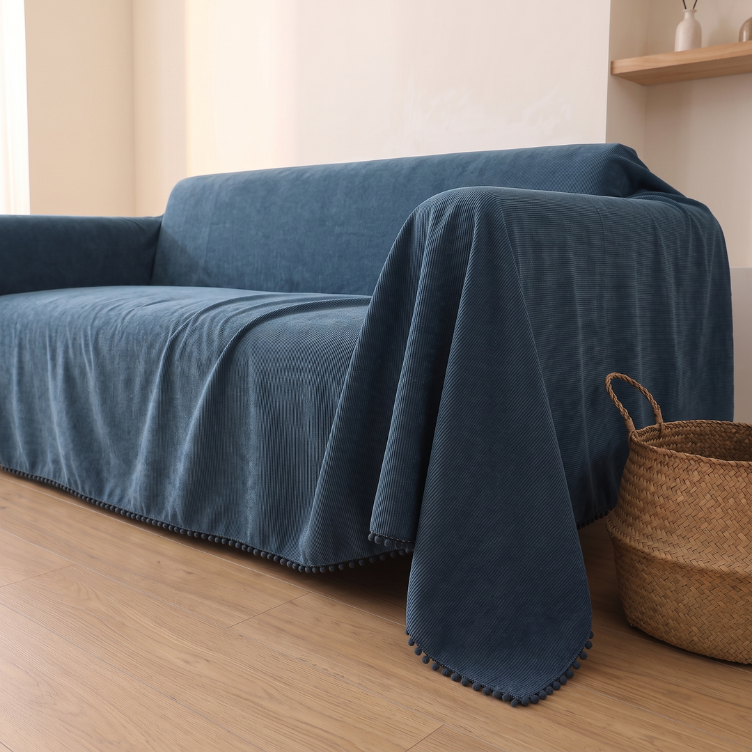 Water-Resistant Couch Cover – Throw Style in Slate Blue – side angle of hanging corner beside a woven basket