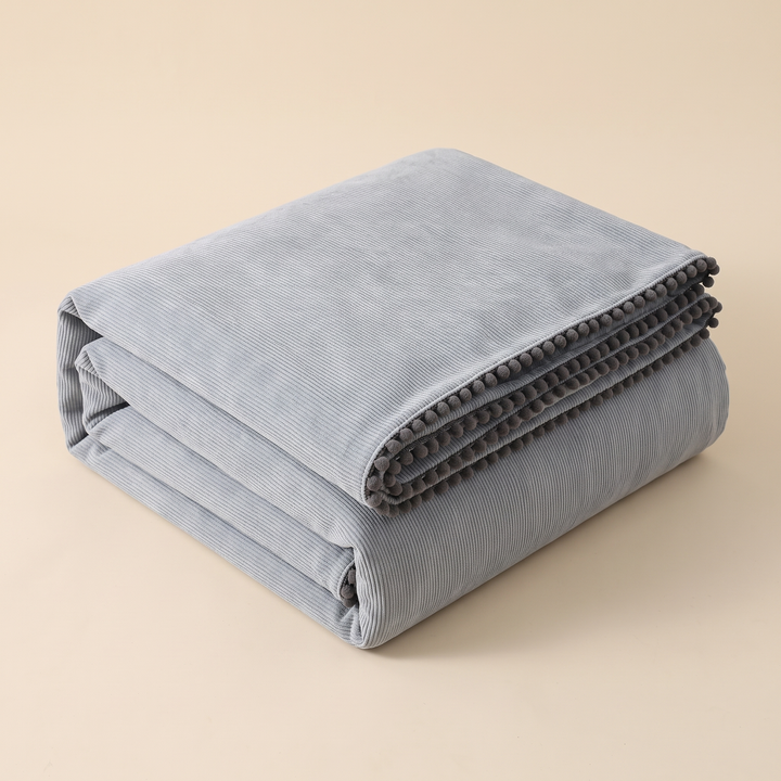Water-Resistant Couch Cover – Throw Style in Gray – folded neatly into a stack on a plain beige background