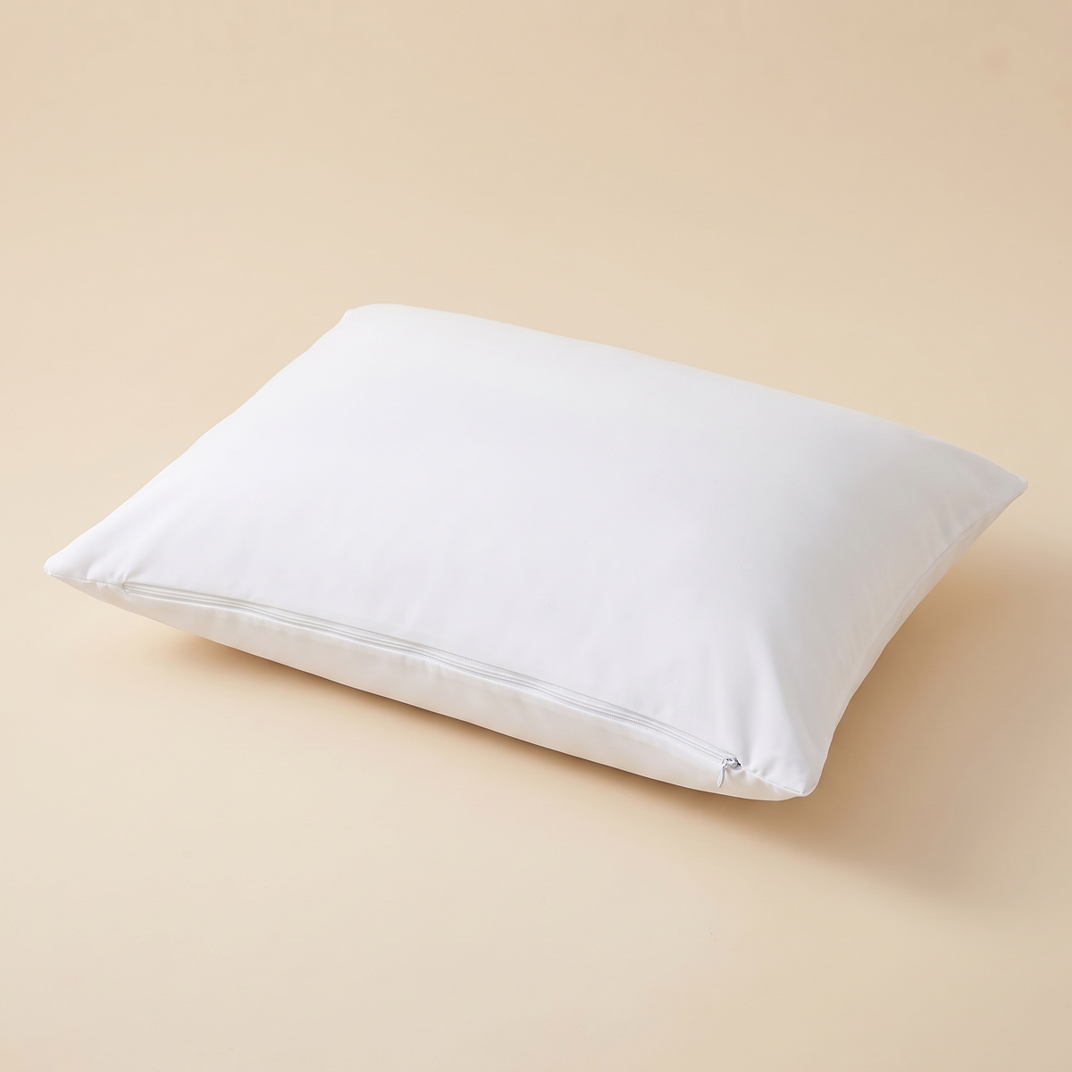 Waterproof Pillow Protector in White – lying flat on a peach backdrop with side zipper visible