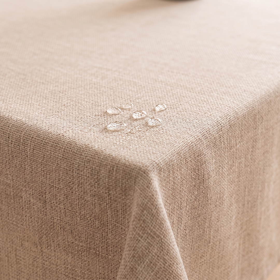 Wipeable Tablecloth – Linen Look in Beige – close-up of water droplets beading on the textured fabric corner