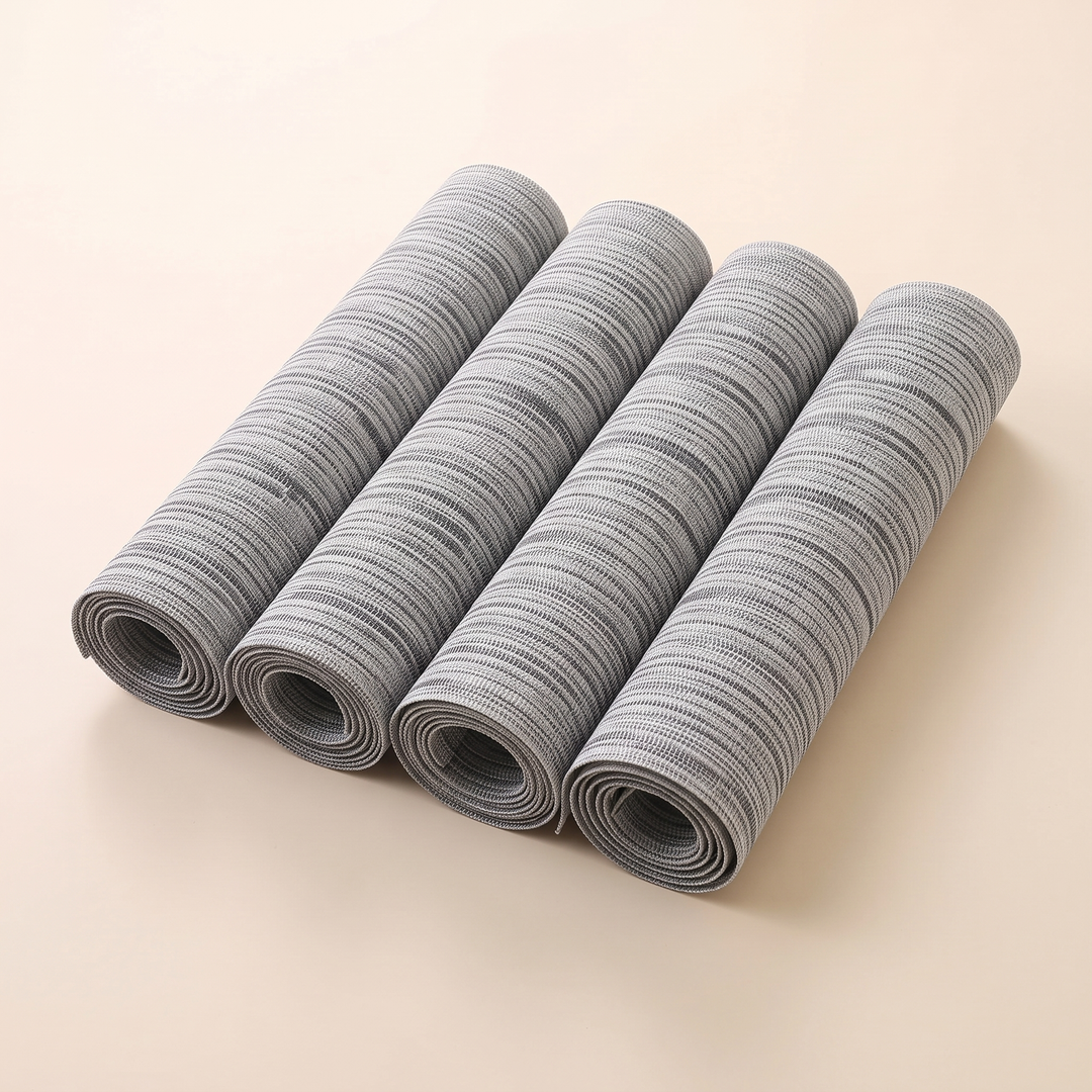 Woven Placemats – Wipe Clean in Gray – Crosshatch – four rolled up mats lined up side by side on plain cream background