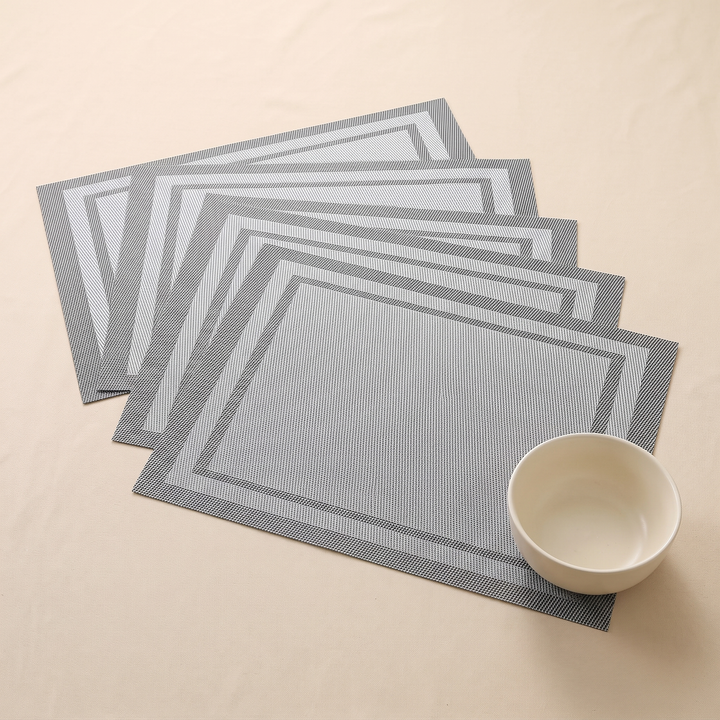 Woven Placemats – Wipe Clean in Gray – Frame – small bowl resting on five overlapping mats, seen from above