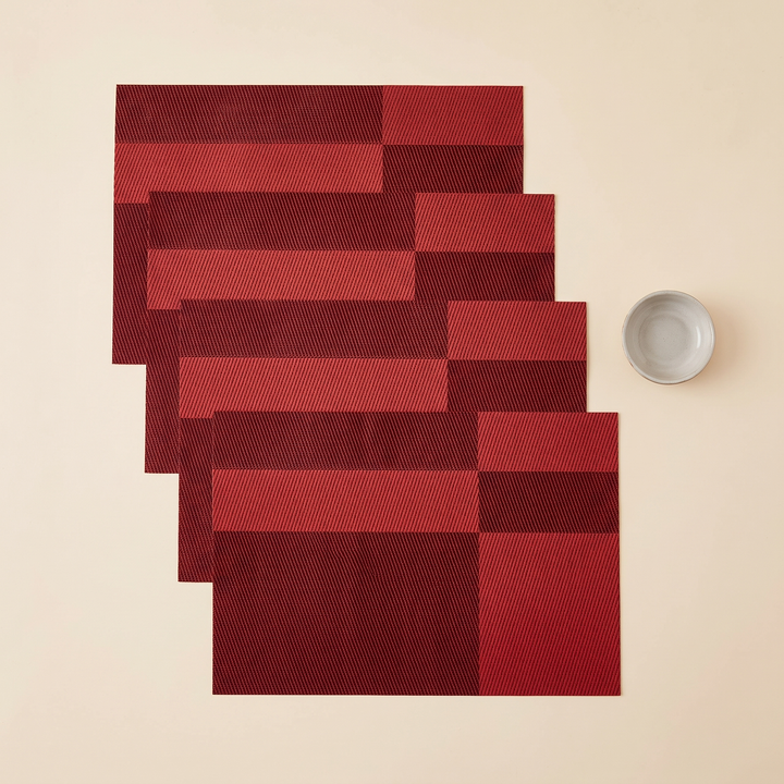 Woven Placemats – Wipe Clean in Red – Two-Tone Block – four mats cascading downward beside a small bowl