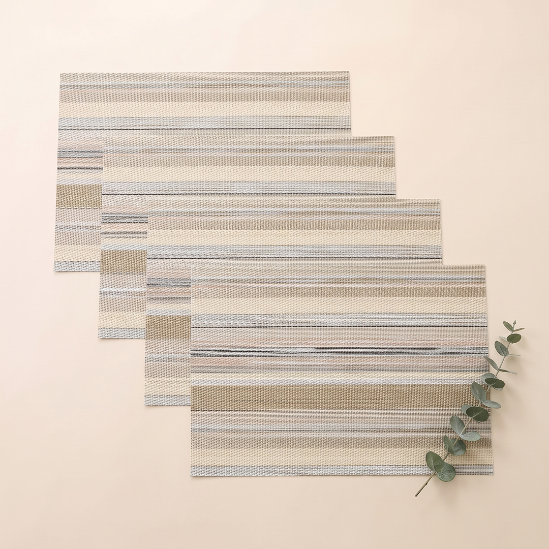 Woven Placemats – Wipe Clean in Sand – Stripe – four mats overlapped diagonally beside a eucalyptus sprig