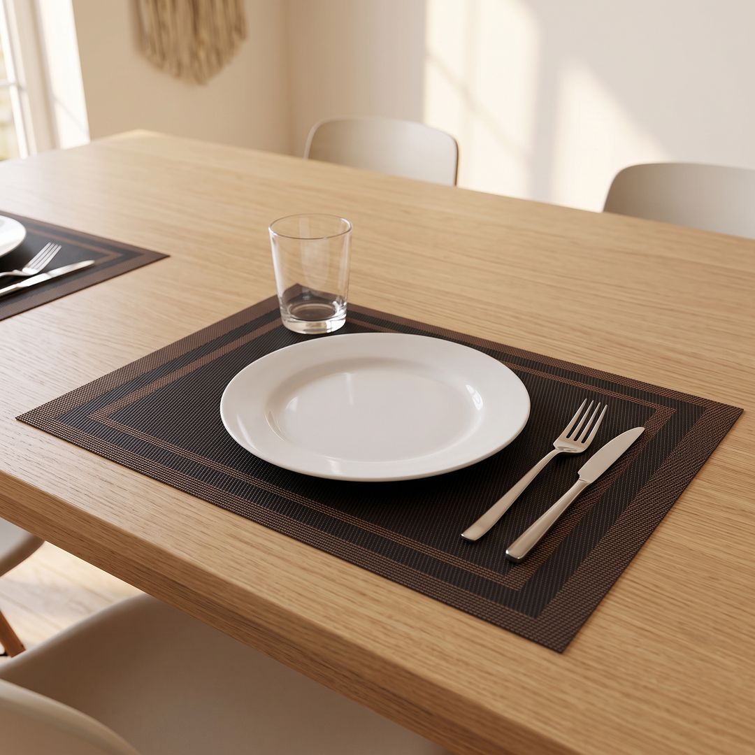 Woven Placemats – Wipe Clean in Black – Frame – set with plate, fork and knife on an oak dining table