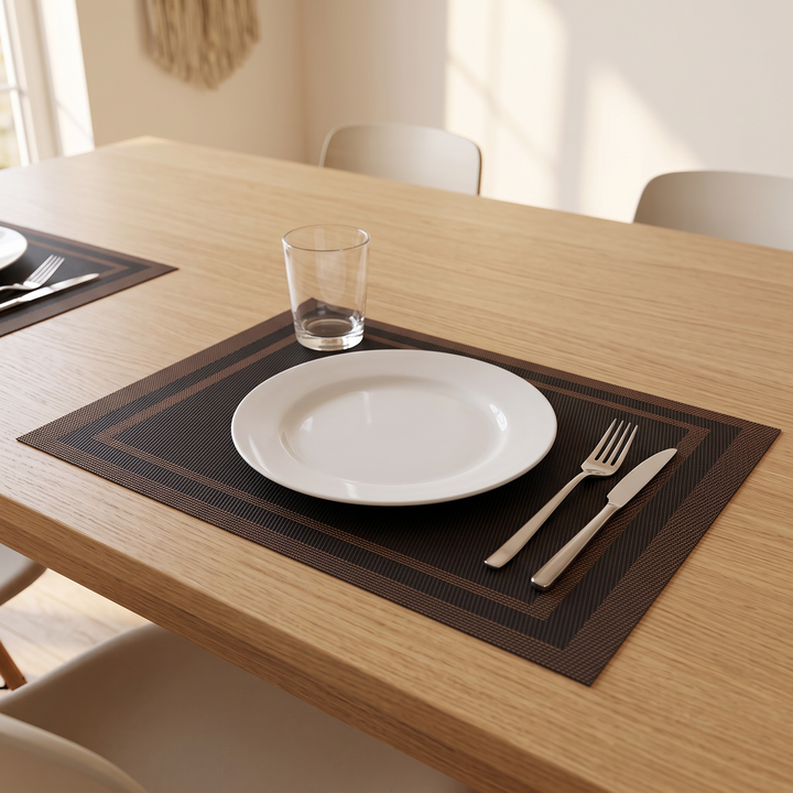 Woven Placemats – Wipe Clean in Black – Frame – set with plate, fork and knife on an oak dining table