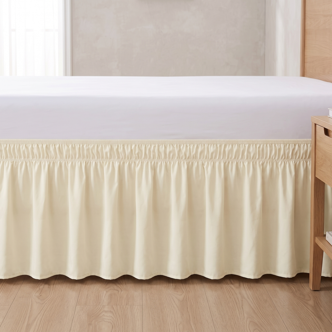 Wrap-Around Ruffled Bed Skirt in Cream – straight-on side view beside a wooden nightstand