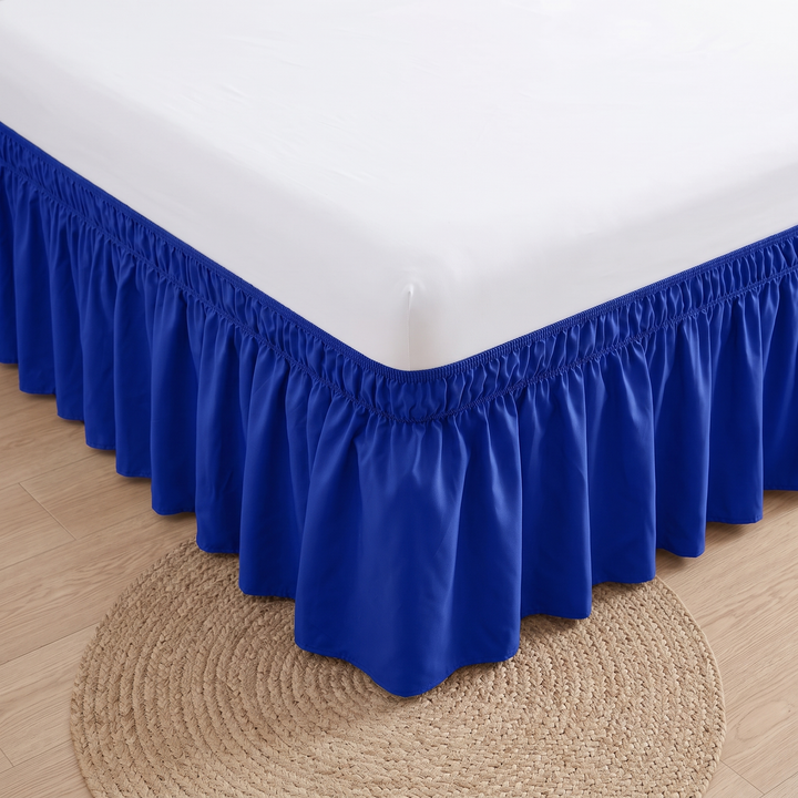 Wrap-Around Ruffled Bed Skirt in Royal Blue – high-angle view of bed corner over round jute rug